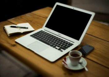 Portatil y café sobre mesa de madera