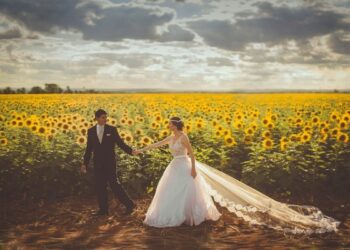 Pareja vestida de boda delante de campo de girasoles