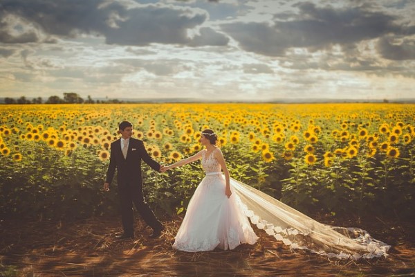 Pareja vestida de boda delante de campo de girasoles