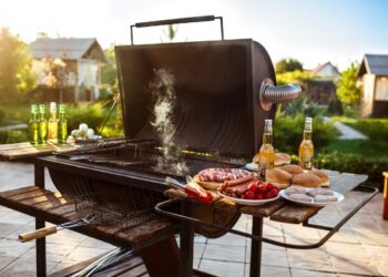 Parrilla en funcionamiento con comida y cerveza al rededor