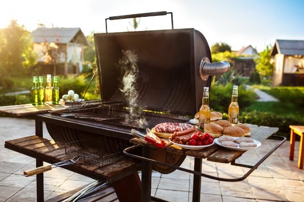Parrilla en funcionamiento con comida y cerveza al rededor