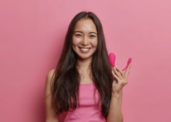 Chica con fondo rosa sujetando juguete sexual